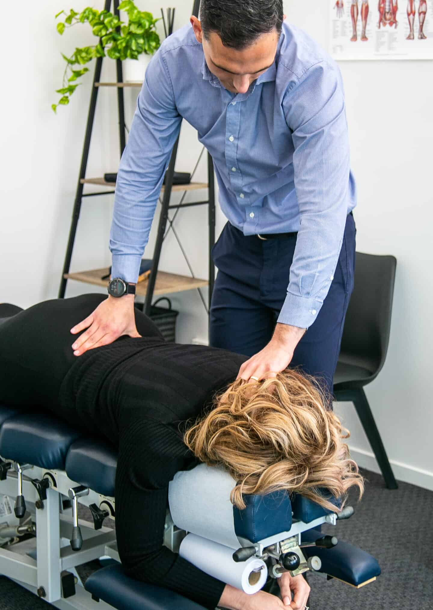 Male Geelong chiropractor performing a spinal palpation assessment of female client