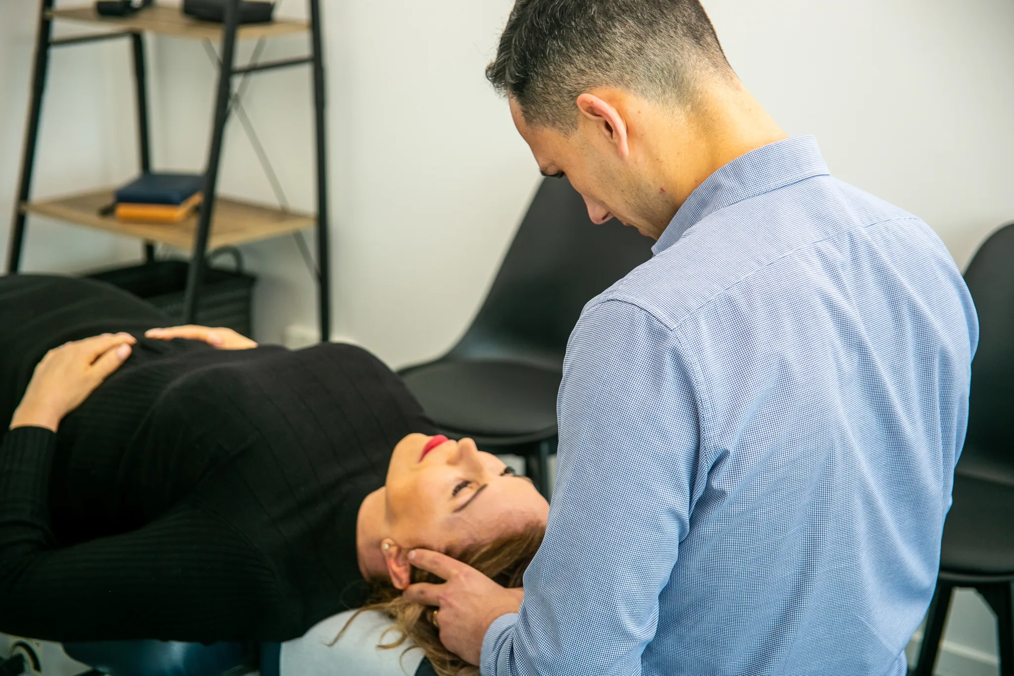 Male Geelong chiropractor performing manual chiropractic therapy to head and jaw of female client