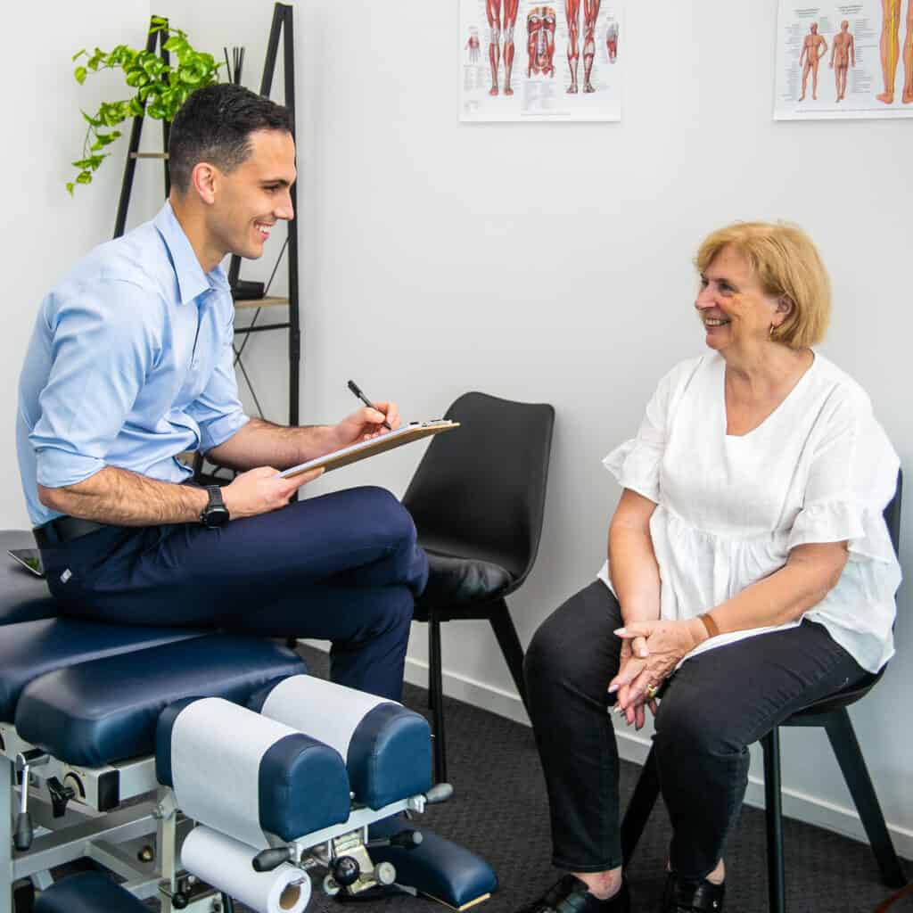 Friendly male Geelong chiropractor performing a detailed history with female client