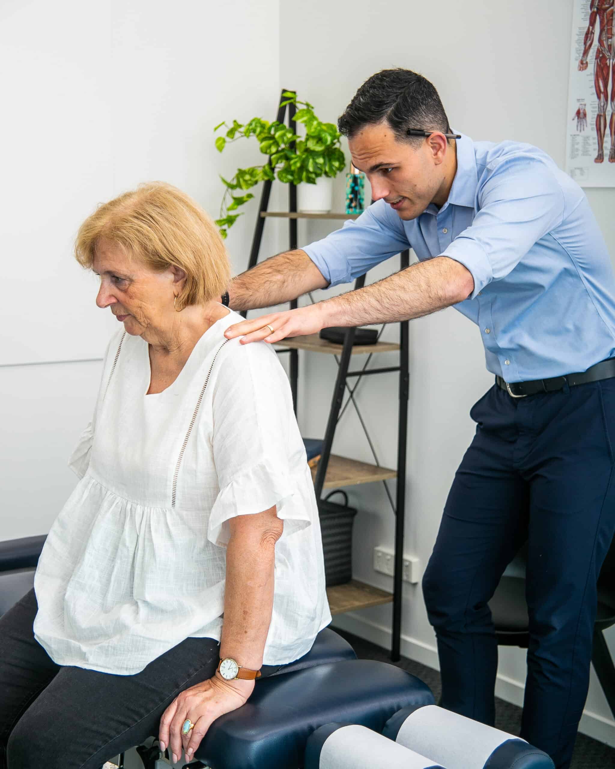 Male Geelong chiropractor performing postural assessment of female client