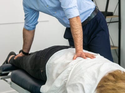 Male Geelong chiropractor performing manual chiropractic treatment to female client