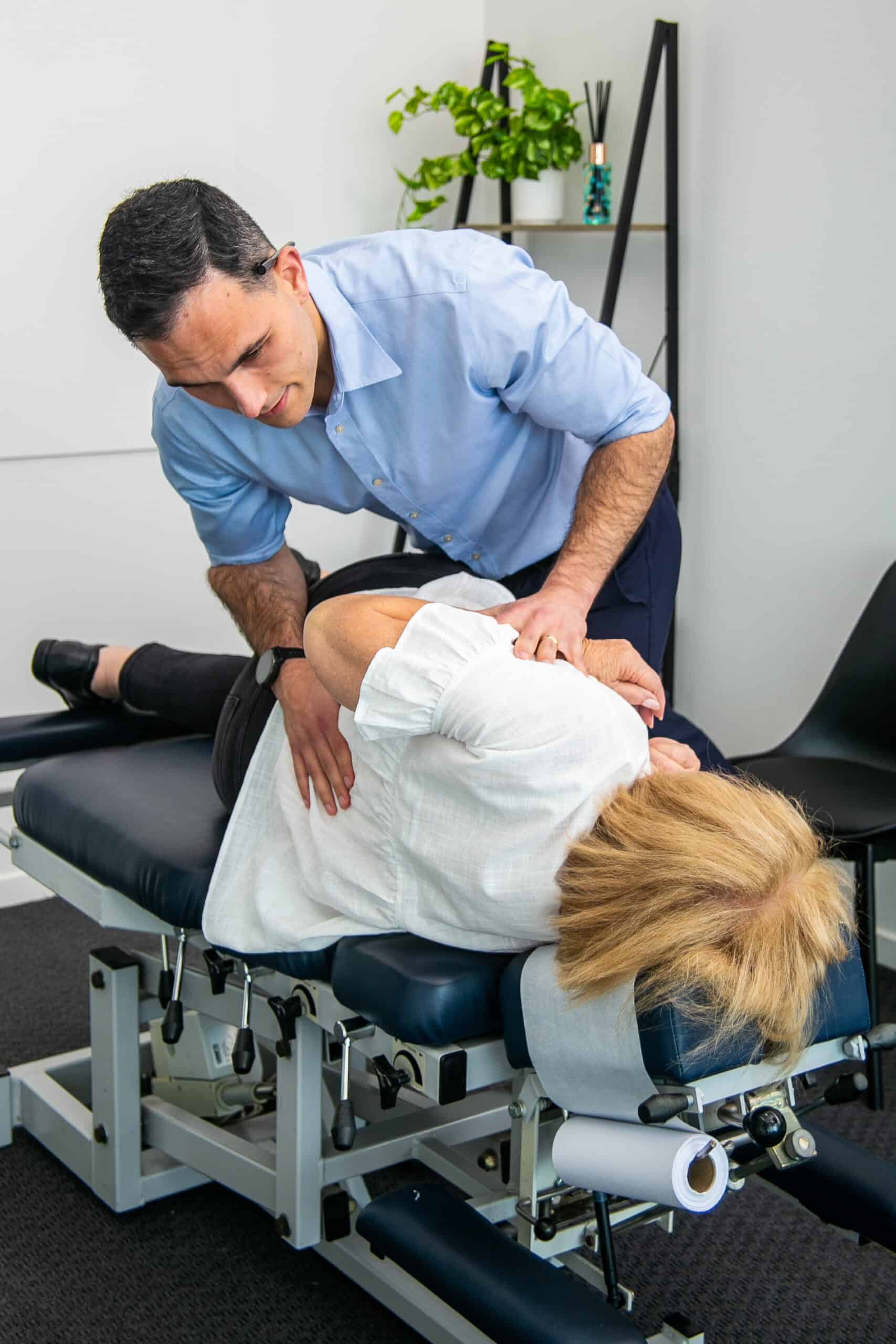 Male Geelong chiropractor performing manual chiropractic adjustment to female client for lower back pain