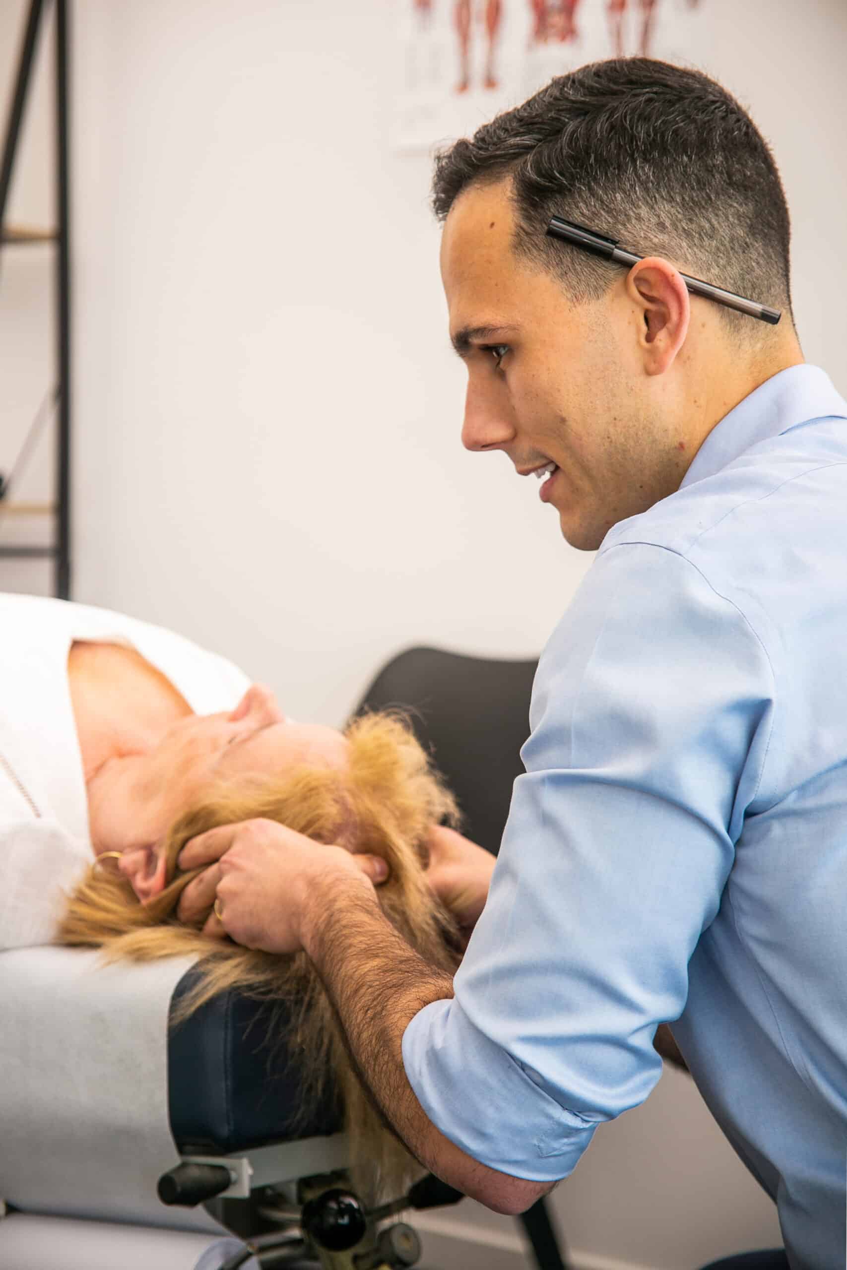 Male Geelong chiropractor performing manual chiropractic care to female client for head pain
