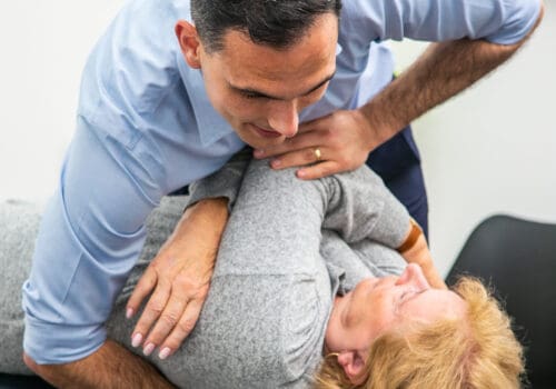 Male Geelong chiropractor performing manual chiropractic adjustment to female client